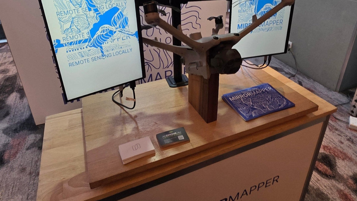Finished Mirrormapper booth at RPAS in Australian Skies 2026: map wall, two screens and a drone on a timber stand
