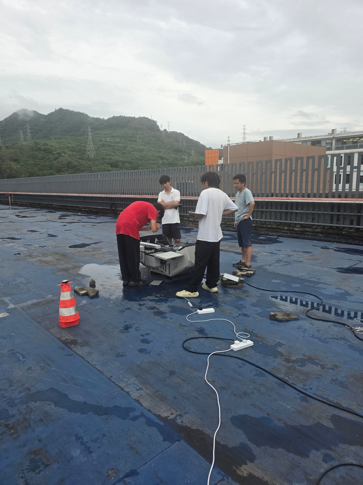 Technicians around an open drone dock on a wet roof during the China trip around UASE Expo week, May 2026