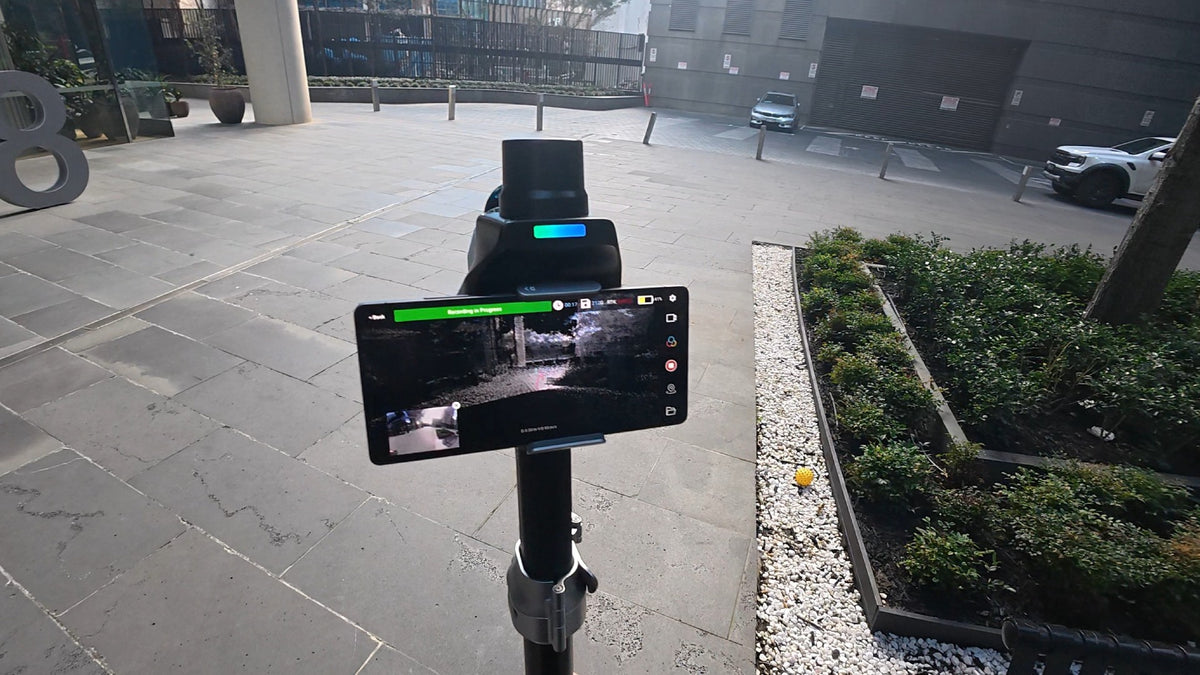 SHARE C1 on a survey pole with a tablet in a courtyard